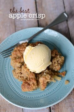 an apple crisp on a blue plate with ice cream in the middle and a fork