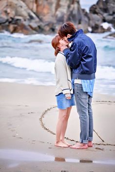 a man and woman standing next to each other on the beach