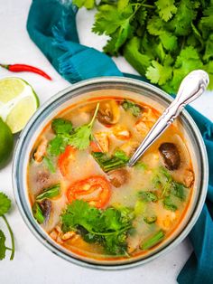 a bowl filled with soup and garnished with cilantro, limes, and mushrooms