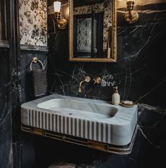 a bathroom with black and white walls, marble counter top and gold accents on the wall