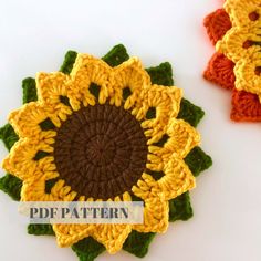 two crocheted sunflowers sitting next to each other on a white surface