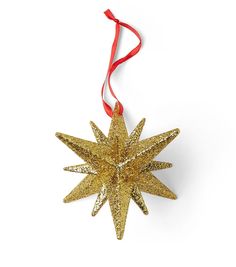 a gold star ornament hanging from a red ribbon