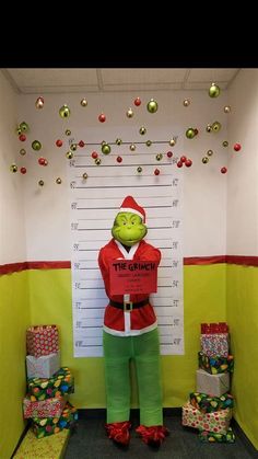 a man dressed as the grinch in front of a christmas themed office cubicle