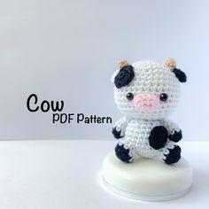 a small crocheted cow sitting on top of a white base with the words cow pattern below it