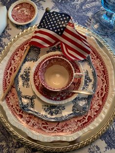 an american flag is on the plate next to cups and saucers