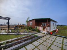 a small house sitting on top of a lush green field next to a tractor parked in front of it