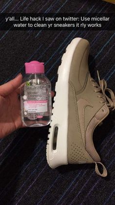 someone is holding a bottle of water next to a pair of shoes