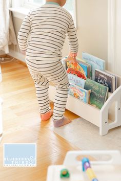 a little boy that is standing in front of a book shelf with books on it