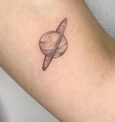 a small saturn tattoo on the arm