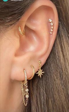 a woman wearing gold ear piercings with stars and moon charms