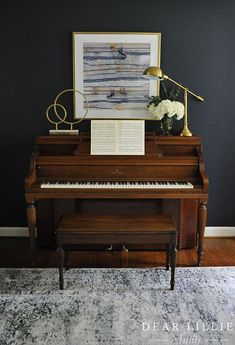 a grand piano in a living room with a painting on the wall above it and a lamp next to it