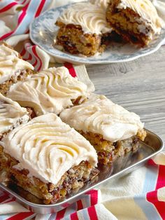 several pieces of cake sitting on top of a metal tray next to plates with white frosting