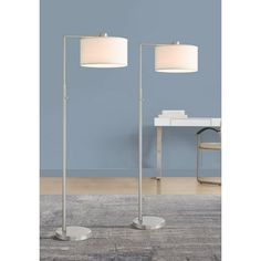 two floor lamps with one light on each side and the other in front of a blue wall