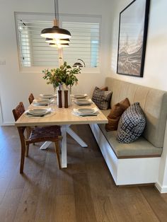 a dining room table and bench with place settings