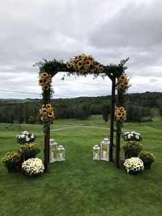 an outdoor ceremony setup with sunflowers and flowers on the grass in front of it