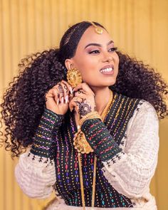 a woman with curly hair wearing an ethnic style outfit and holding a gold coin in her hand