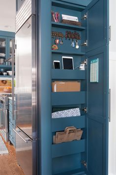 an open pantry door in a kitchen with blue walls and drawers on the bottom shelf