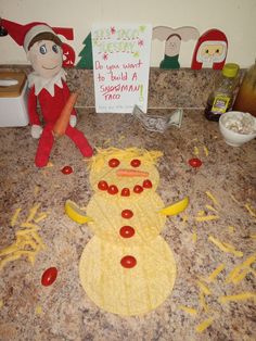 an elf making a snowman made out of doughnuts on the kitchen counter