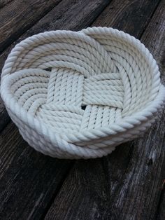 a white rope that is on top of a wooden table and has knots in it