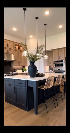 a large kitchen with an island in the middle and chairs around it, along with lights