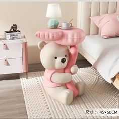 a white teddy bear sitting on top of a pink table next to a bed with pillows