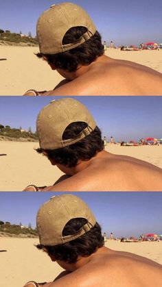 the back of a man's head wearing a baseball cap on top of a sandy beach