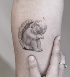 a woman's arm with a small tattoo of an angel holding a baby in her arms