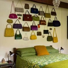 there are many purses hanging on the wall above the bed and in front of the bed