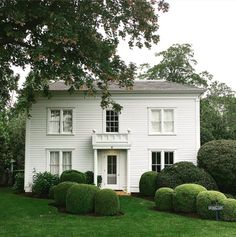 a white house surrounded by hedges and trees