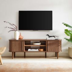 a flat screen tv mounted to the side of a wooden entertainment center in a living room