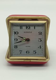 a small red and gold clock sitting on top of a table