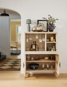 a shelf with glasses and bottles on it in a living room next to a staircase