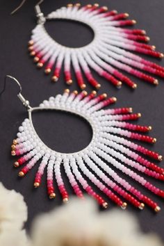 two pairs of white and red beaded hoop earrings on top of a black surface