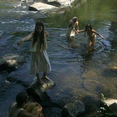 some people are standing in the water near rocks