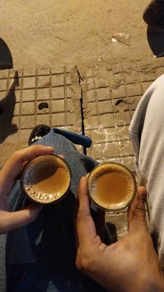 two people sitting on the ground with cups in their hands