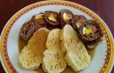 a plate filled with meat and bread on top of a wooden table