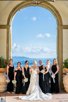 a group of women standing next to each other on top of a stone floor under an archway