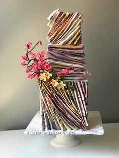 a multi - tiered cake with flowers and branches on the top is made out of newspaper strips