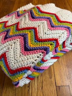 a multicolored crocheted blanket sitting on top of a wooden floor