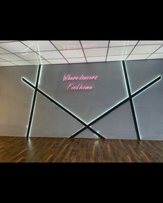 an empty room with wooden floors and neon lights