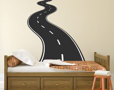 a bedroom with a bed, dresser and wall decal in the shape of a road