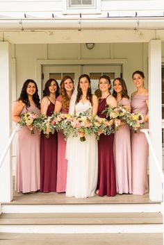 a group of women standing on top of a porch next to each other holding bouquets