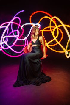 a woman sitting on a chair in front of some colorful light circles and holding a red frisbee