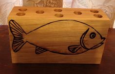 a wooden block with an image of a fish painted on the side and holes in it