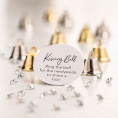 a ring the bell for the newlyweds to share a kiss is surrounded by tiny gold and silver bells