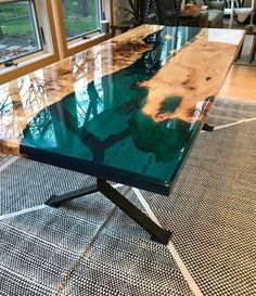 a table that is sitting on the floor in front of some windows and rugs