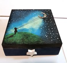 a box with a painting on the lid that has a person flying a kite in the sky