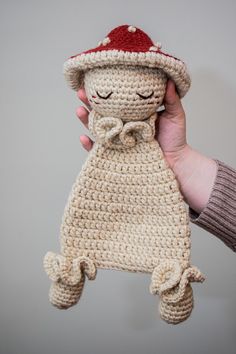 a hand holding a crocheted stuffed animal with a hat on it's head