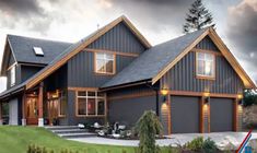 a large gray house sitting on top of a lush green field next to a forest