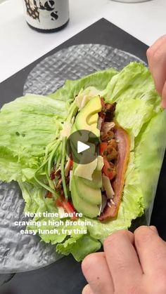 a person is holding a lettuce wrap with meat and avocado on it